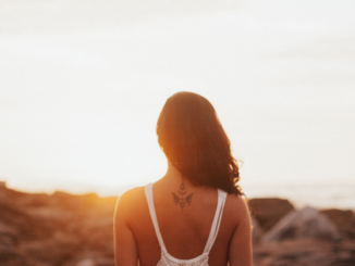 A woman, alone, looking at the sunset with her back turned