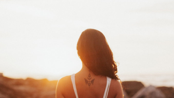 A woman, alone, looking at the sunset with her back turned